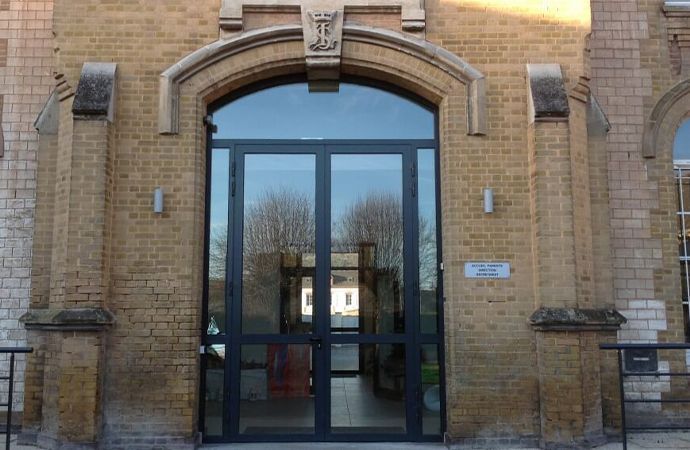 Entrée d'un bâtiment en briques avec double porte vitrée et ornementation en pierre cintrée