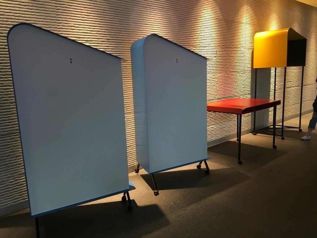 Trois paravents bleus, une table rouge et une lampe jaune dans une pièce faiblement éclairée