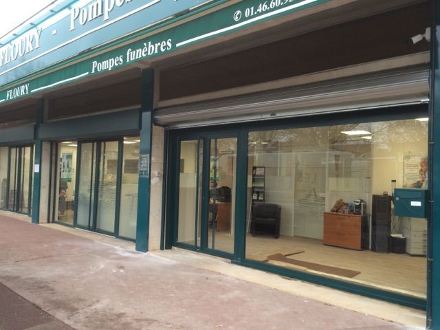 Façade de magasin avec auvent vert et grandes vitrines donnant sur un trottoir