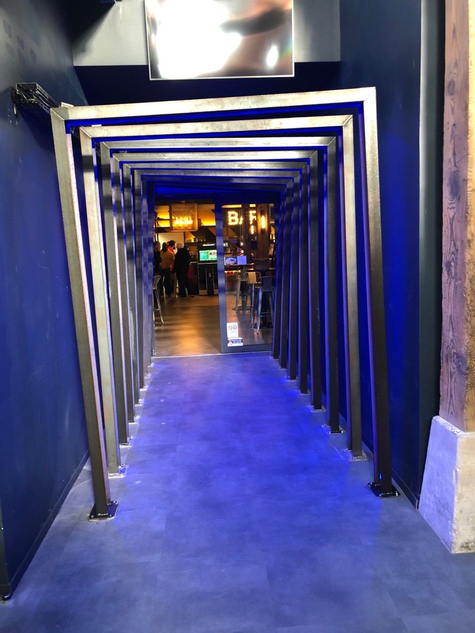 Entrée du tunnel éclairée en bleu menant à un espace intérieur à l'éclairage chaleureux