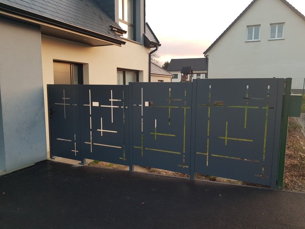 Portail d'allée en métal gris foncé entre des maisons beiges au crépuscule
