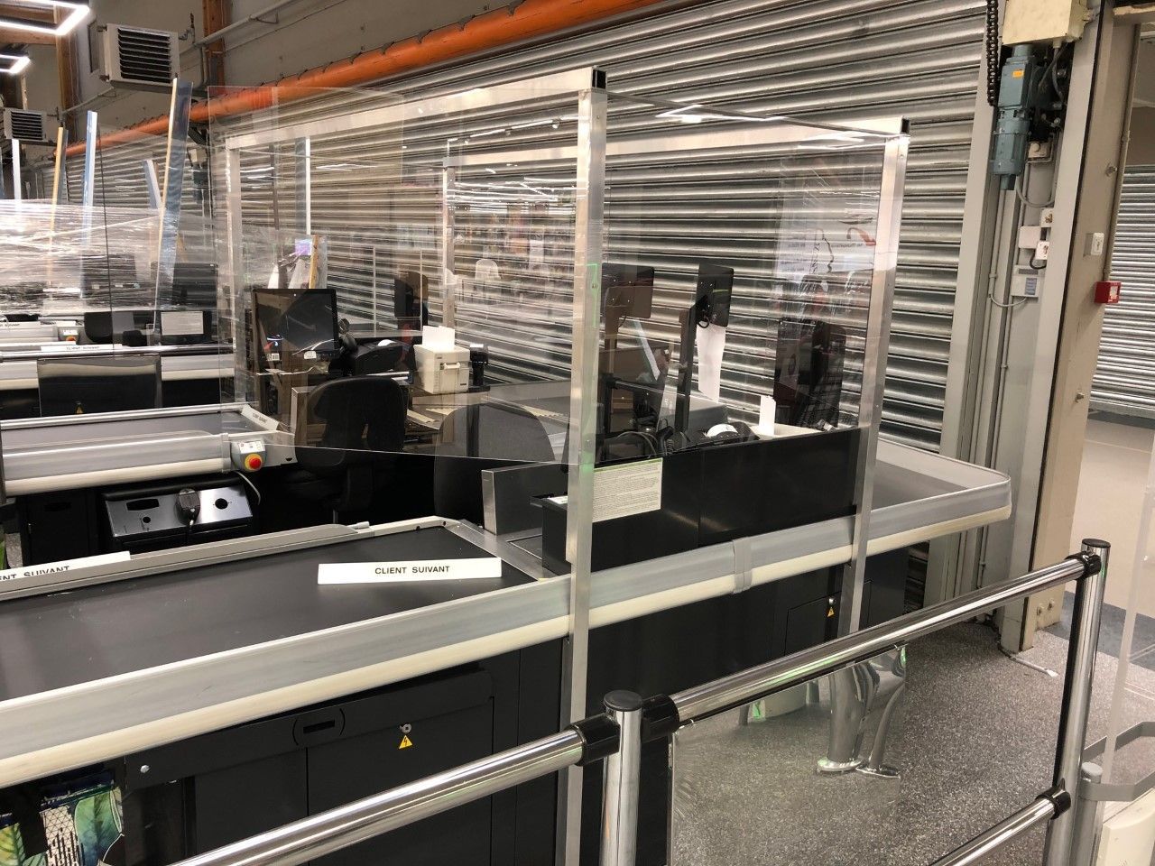 Ligne de convoyage d'usine avec barrières de sécurité en plastique transparent et rails métalliques dans un environnement industriel
