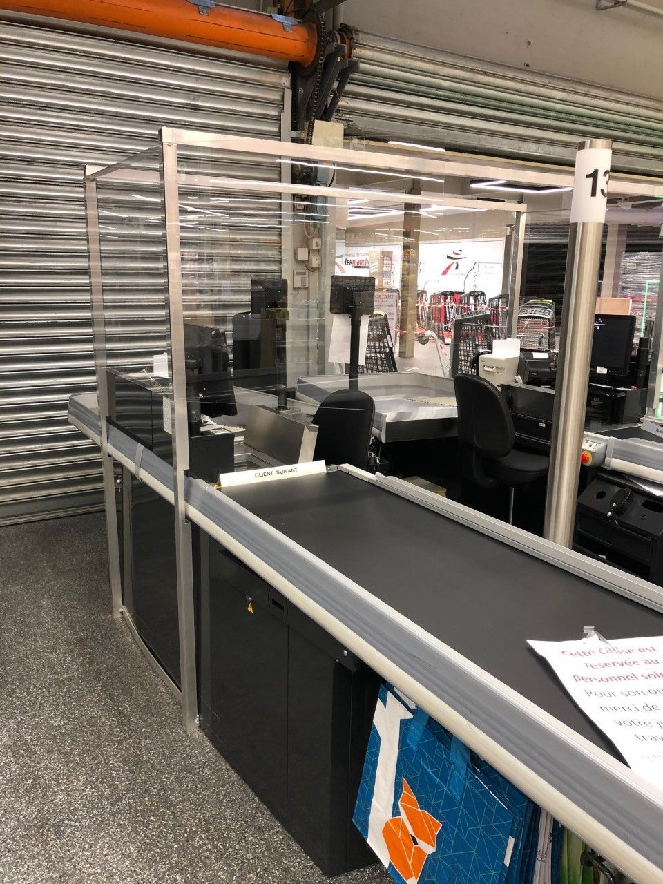 Point de contrôle aéroportuaire avec tapis roulant, écran de protection transparent et chaises d'attente près d'un rideau métallique fermé