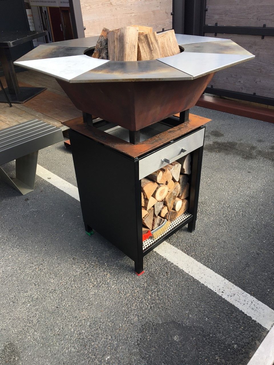 Foyer extérieur à bois avec rangement pour bûches en dessous, sur dalle