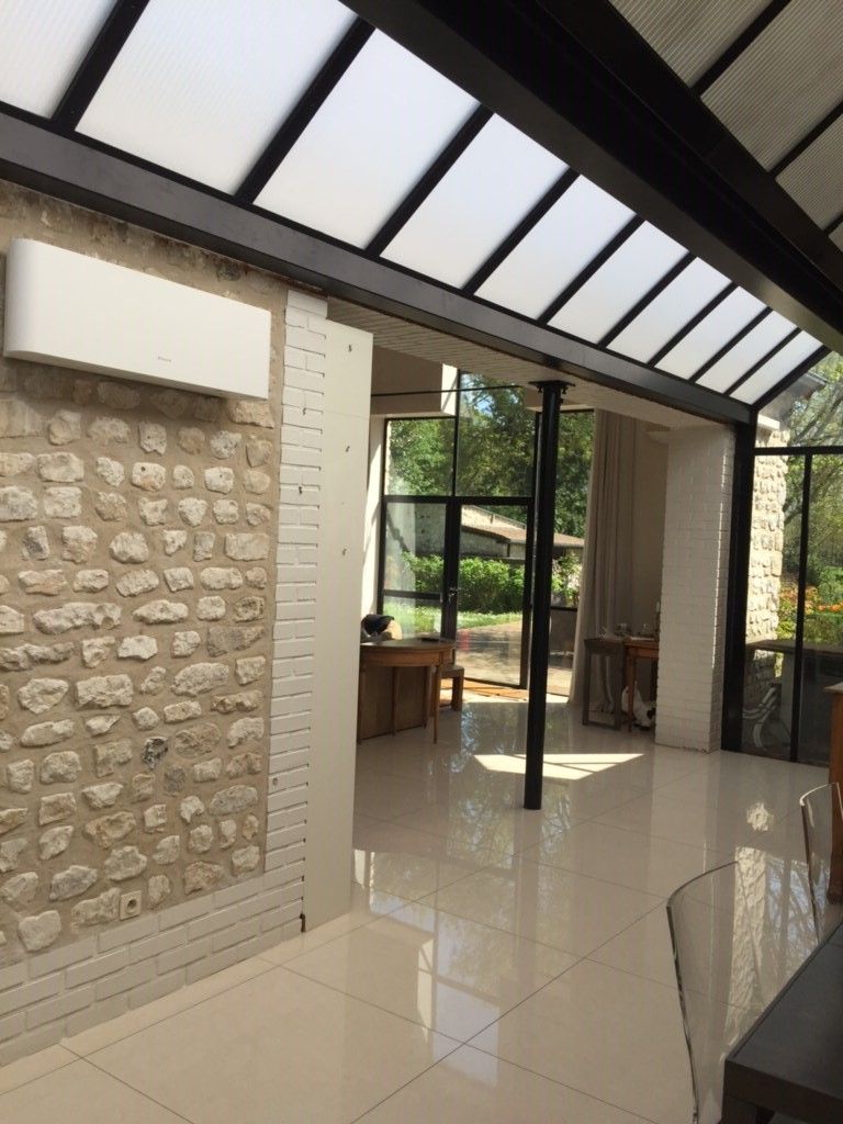 Intérieur moderne avec mur en pierre, sol brillant et fenêtres de toit inclinées donnant sur un jardin.