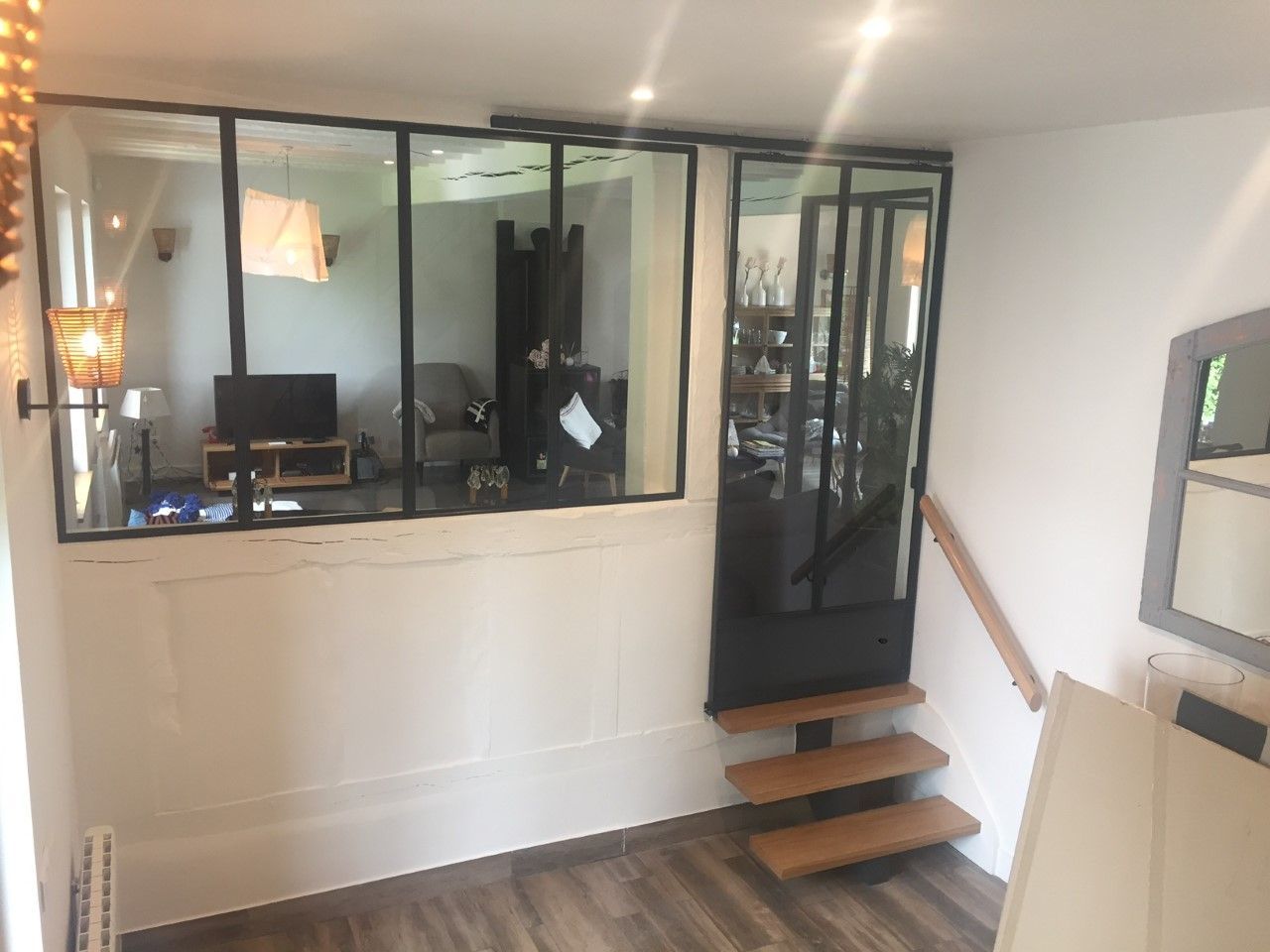 Vue intérieure d'un bureau à domicile avec une cloison vitrée et un petit escalier menant à une porte.