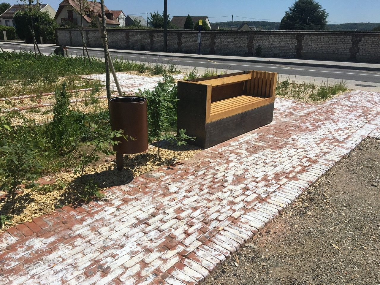 Banc et poubelle à côté d'un chemin pavé dans un espace extérieur ensoleillé