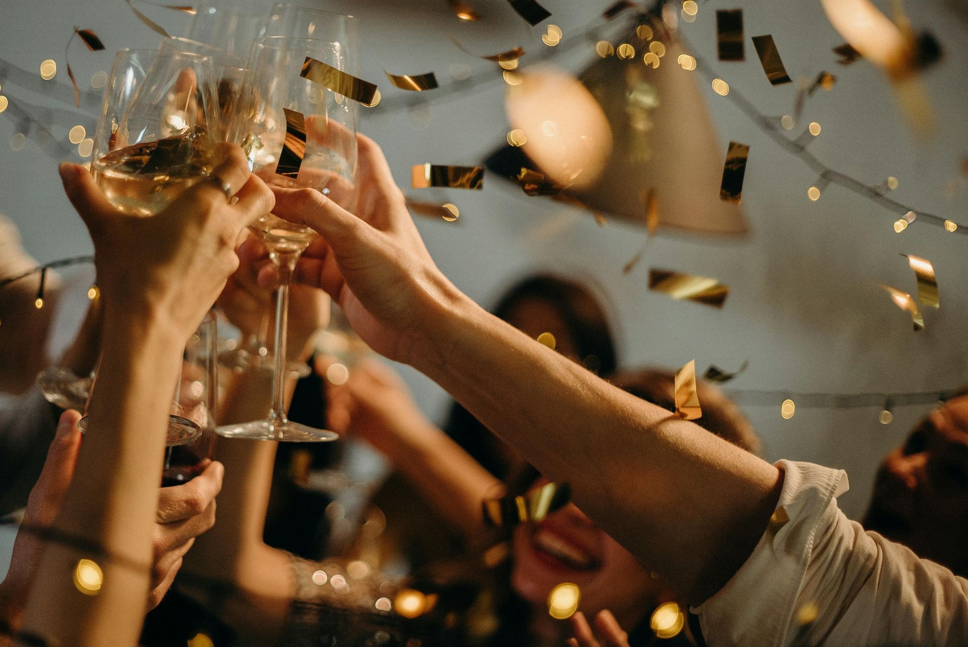 People toasting with champagne glasses, celebrating, with confetti.