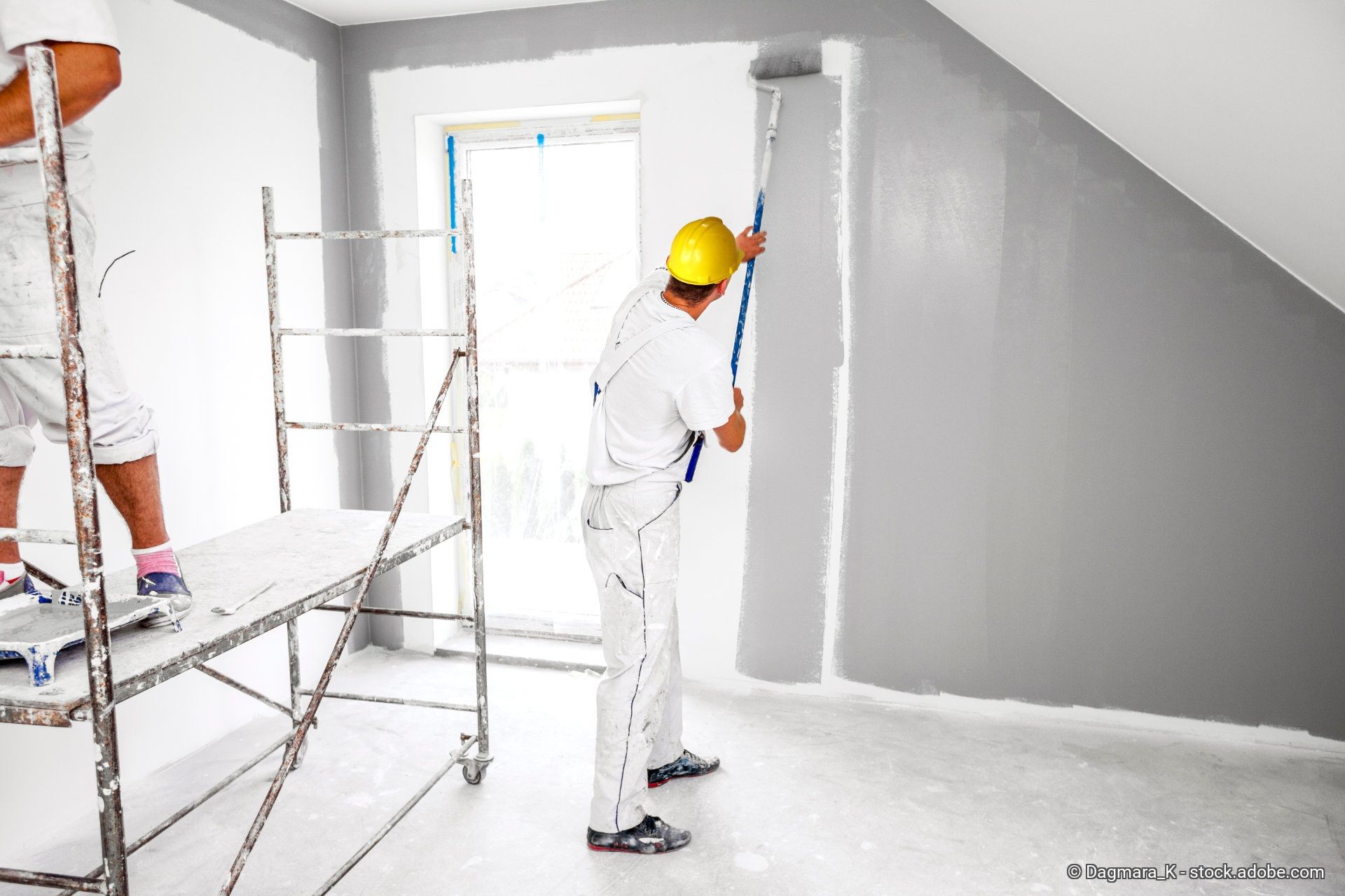 Zwei Maler streichen ein Dachbodenzimmer