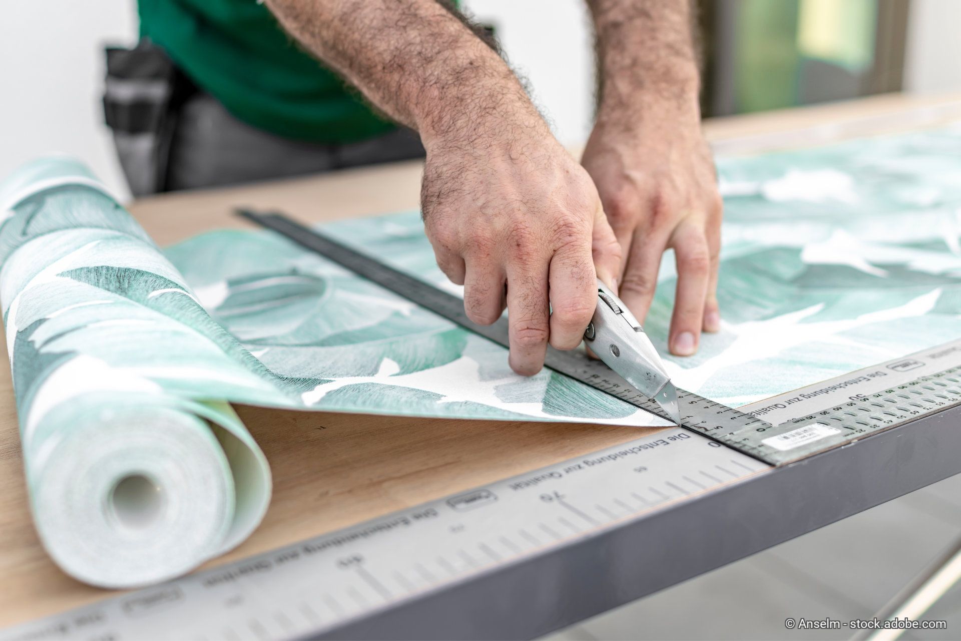 Ein Maler schneidet eine gemusterte Tapete zu