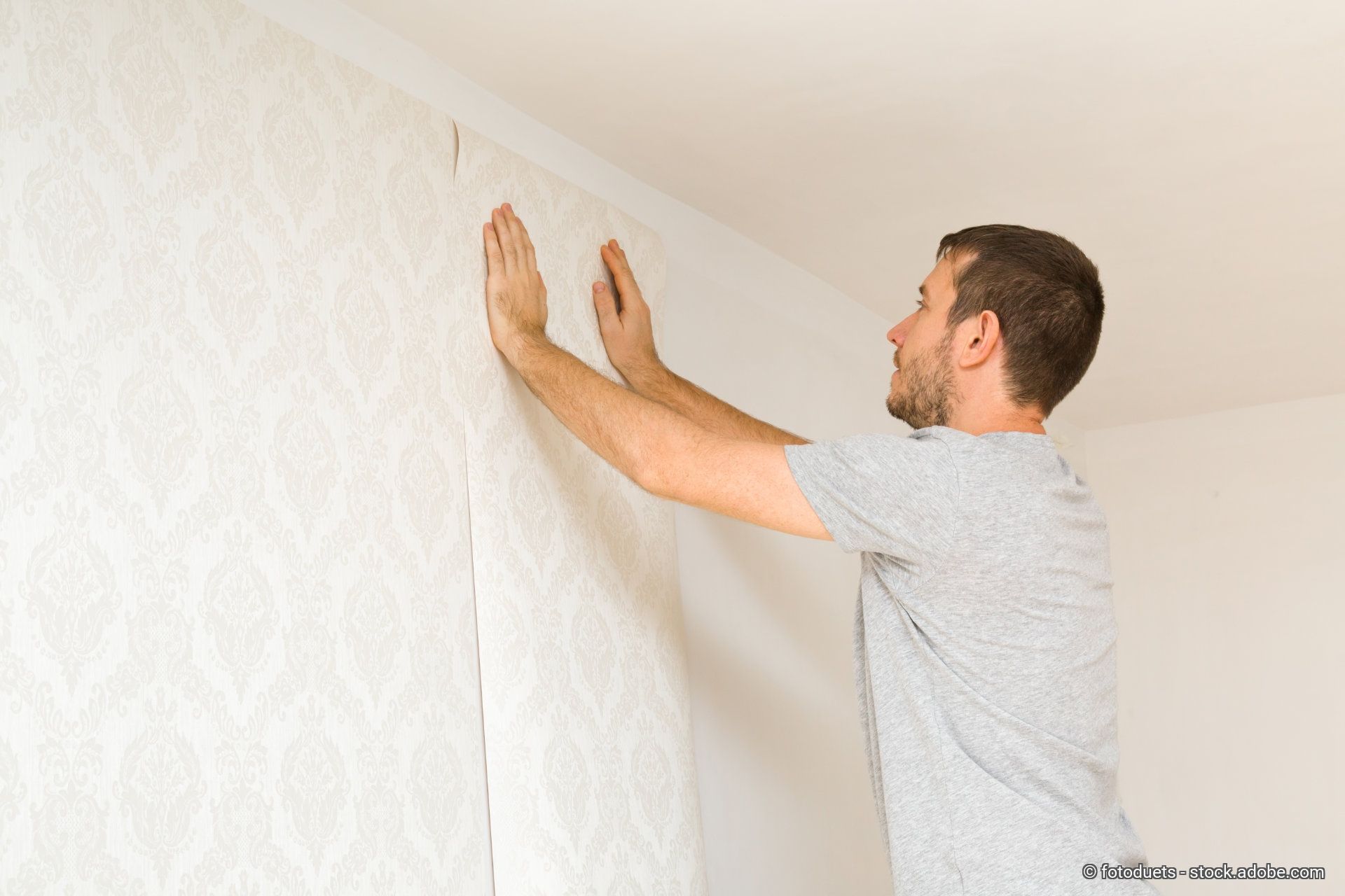 Ein Maler tapeziert die Wand eines Kunden