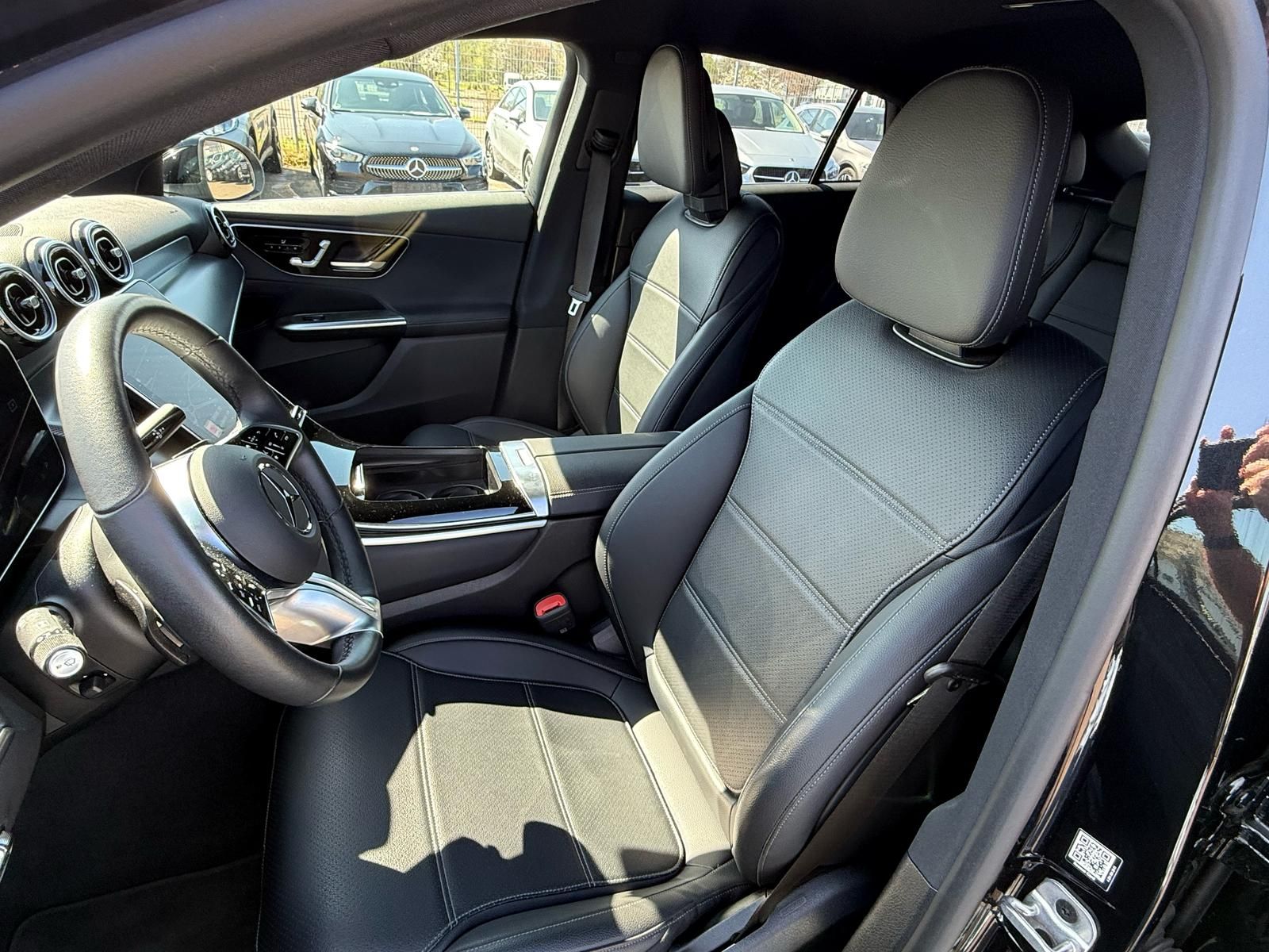 Intérieur de voiture avec sièges avant, volant et console centrale noirs, visible à travers la porte ouverte