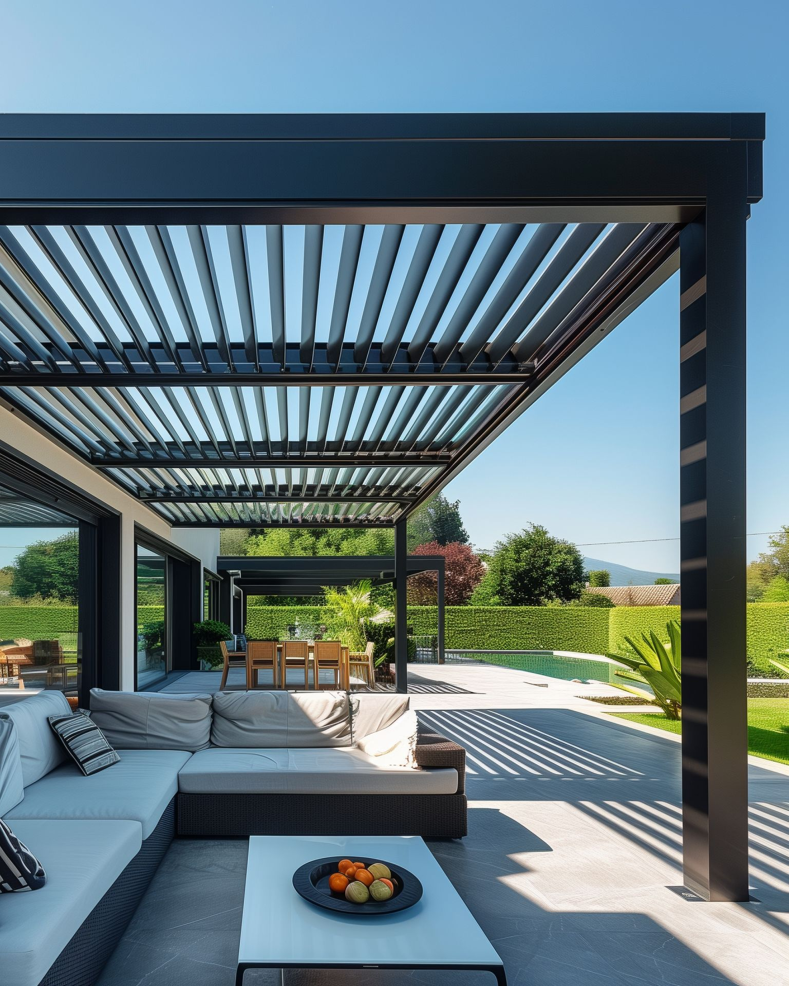 Terrasse extérieure moderne avec une pergola noire au-dessus d'un canapé d'angle et d'une table basse.