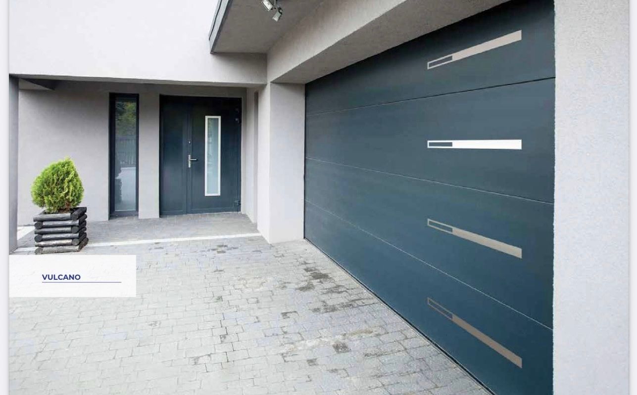 Extérieur de maison moderne avec porte de garage grise, entrée et allée pavée.