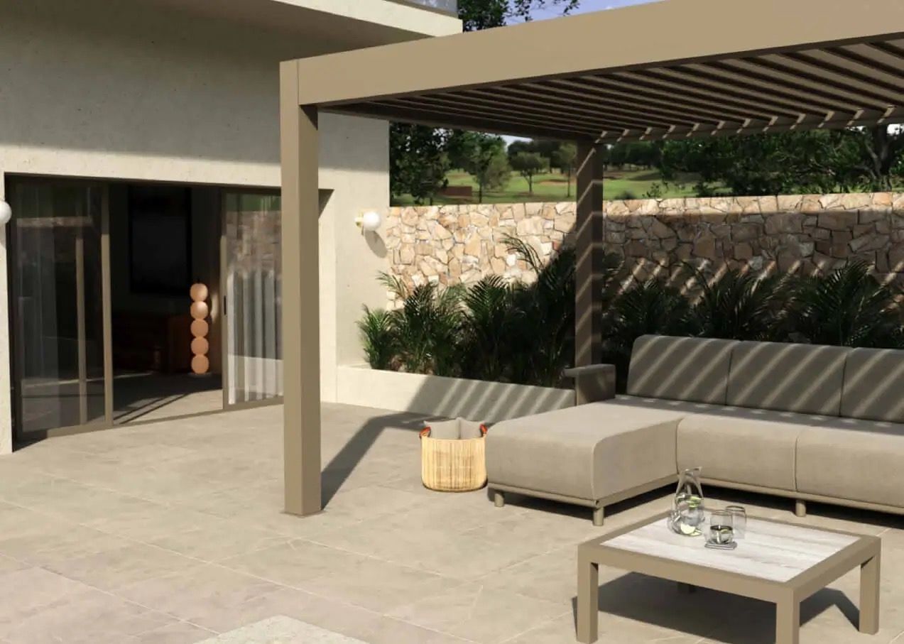 Pergola beige avec sièges sur une terrasse. Vue sur un mur de pierre, de la verdure et une porte-fenêtre coulissante.