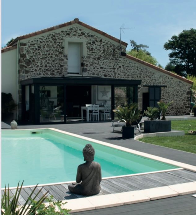Maison en pierre avec piscine, statue de Bouddha et espace repas extérieur.