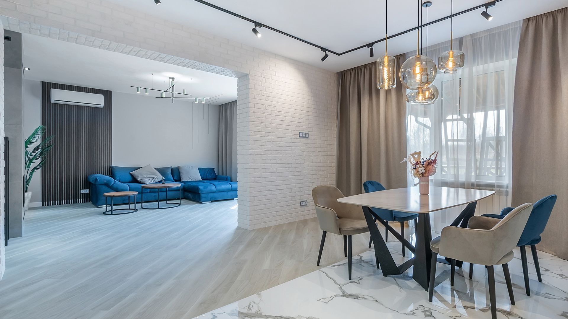 Una sala de estar con una mesa de comedor y sillas y un sofá azul.