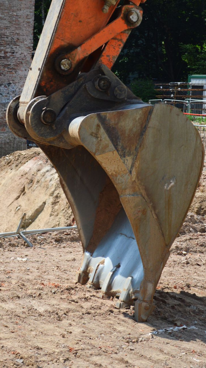 Godet d'excavatrice creusant le sol sur un chantier de construction.