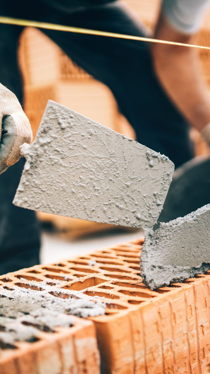 Un maçon applique du mortier à la truelle sur une brique.