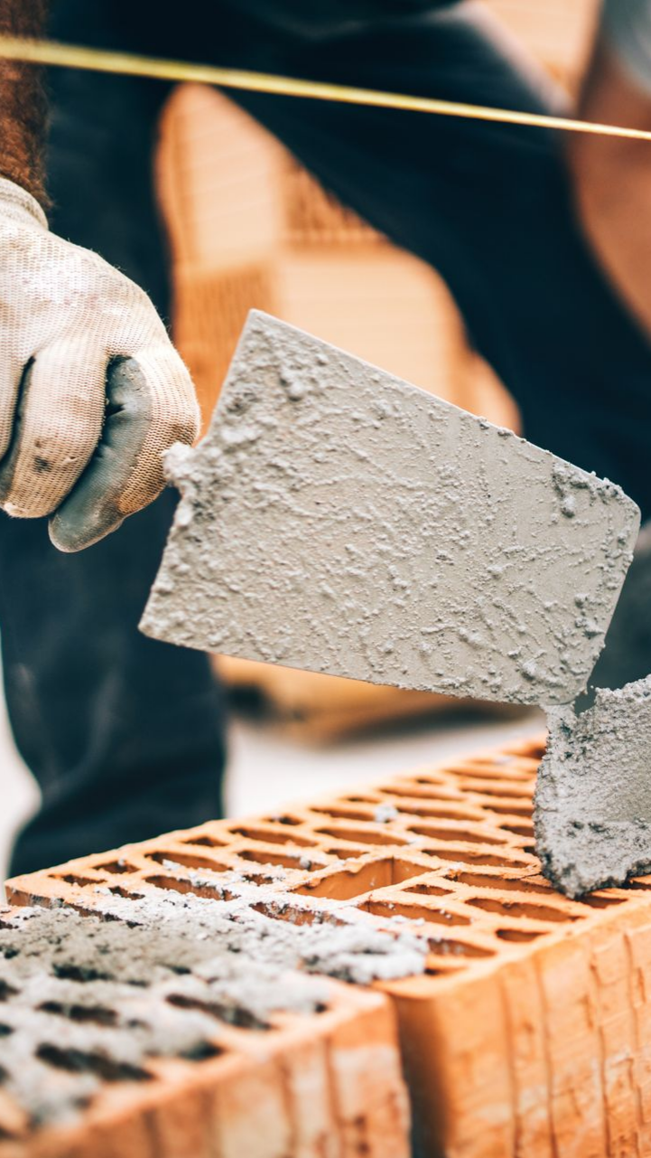 Un maçon applique du mortier sur une brique à l'aide d'une truelle.