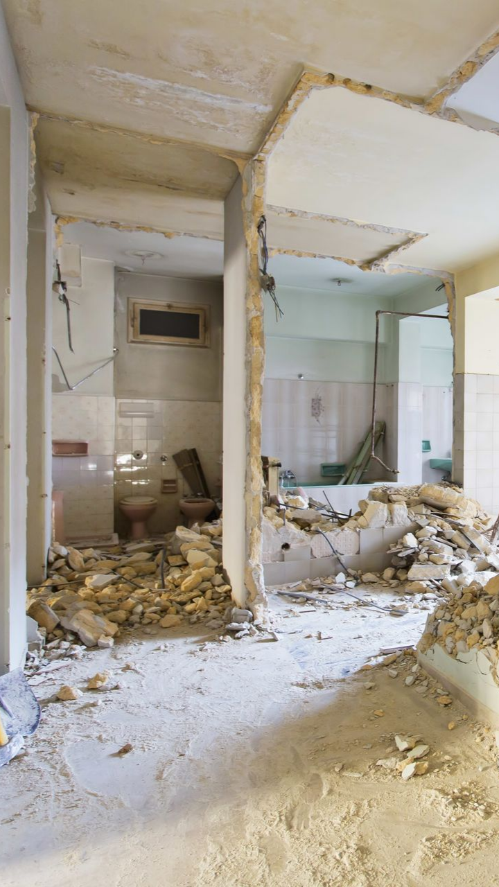 Intérieur d'une pièce en cours de démolition, débris éparpillés au sol. Murs et plafond partiellement détruits.