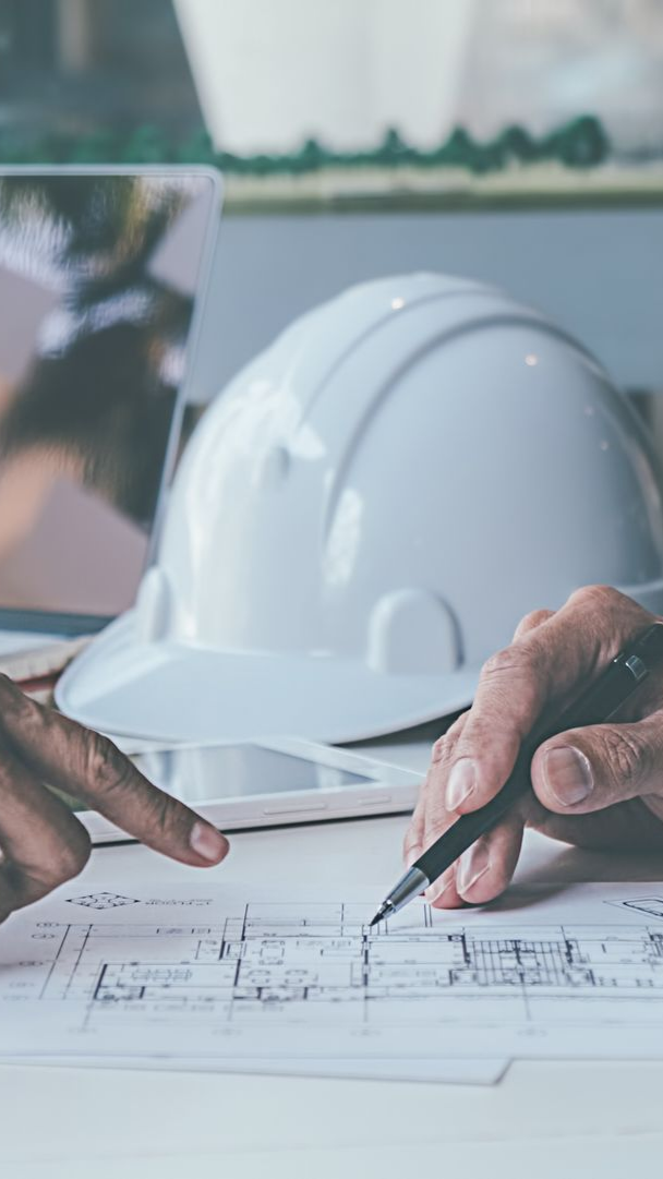 Des plans, un casque de chantier blanc se trouve à proximité.