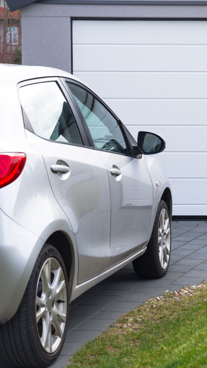 Voiture à hayon argentée garée sur une allée pavée à côté d'un garage blanc.