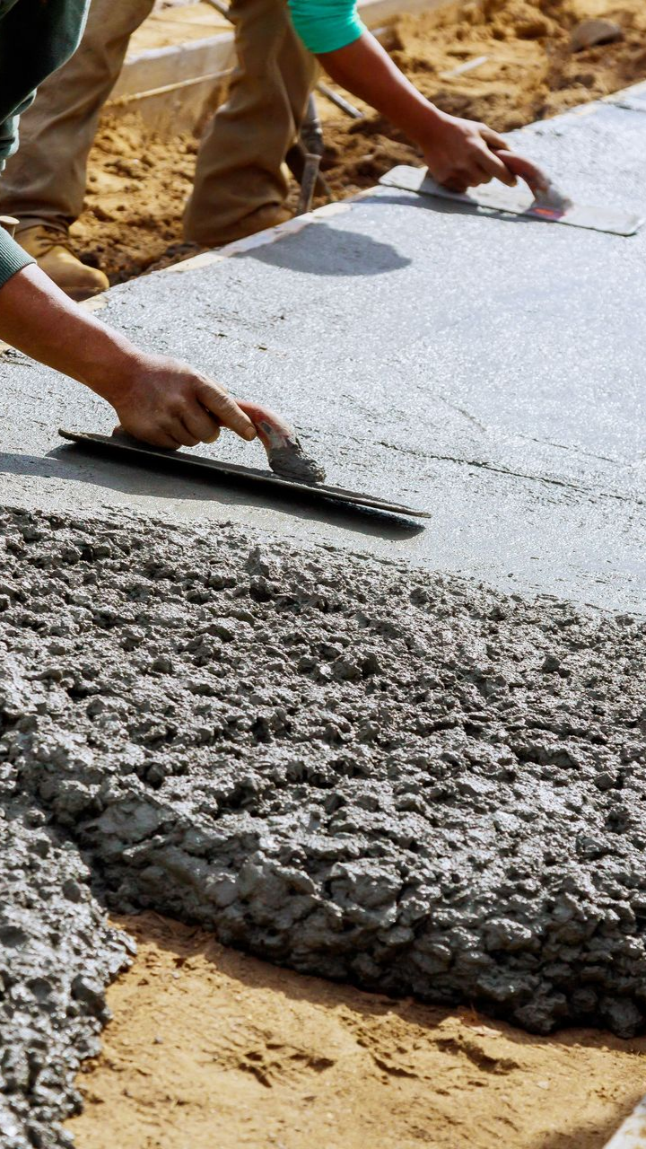 Des ouvriers lissent le béton frais à la truelle pour créer un trottoir.