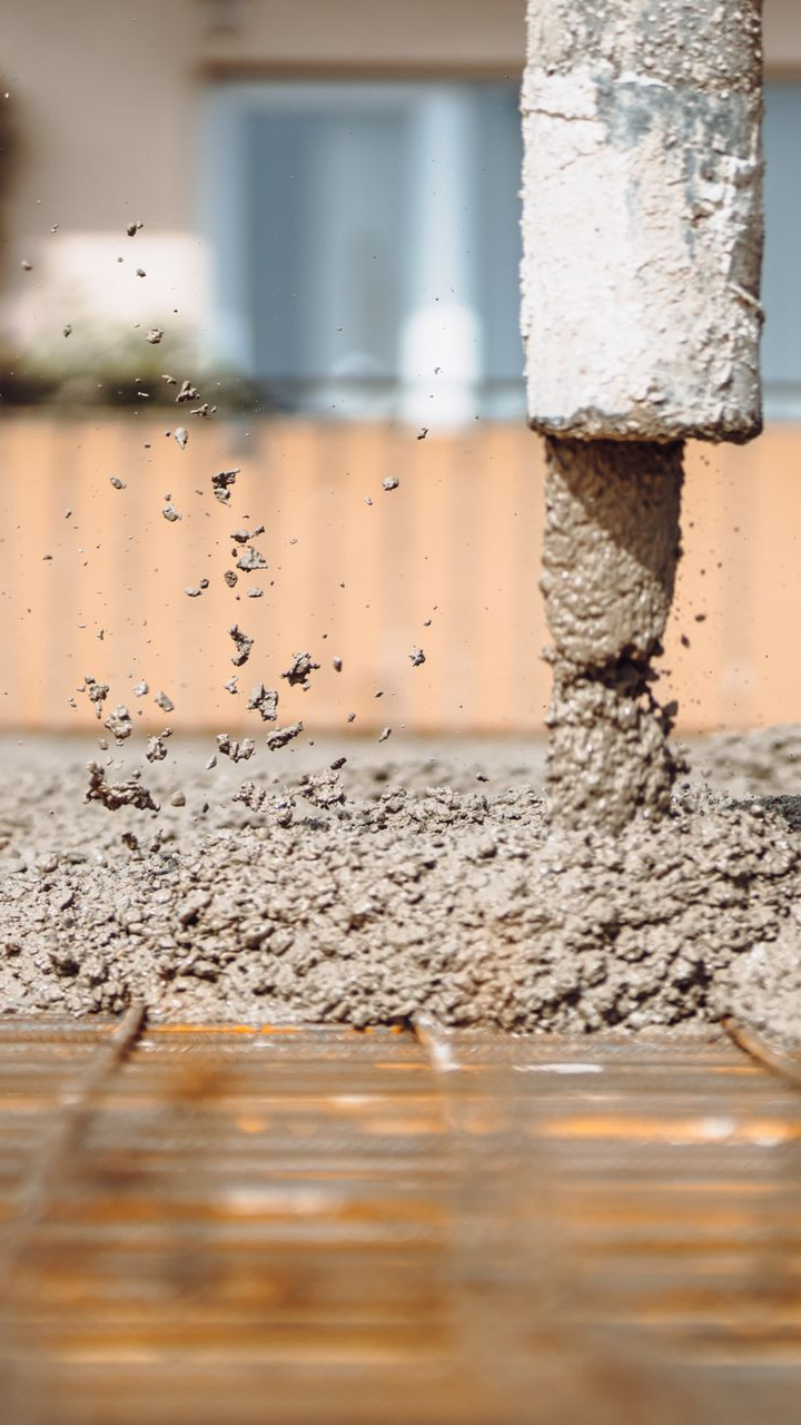 Coulage de béton d'un tuyau sur des barres d'armature, chantier de construction.