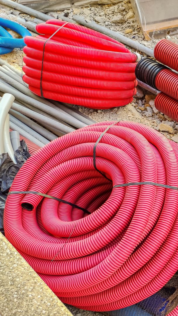 Bobines de conduit électrique ondulé rouge sur un chantier.