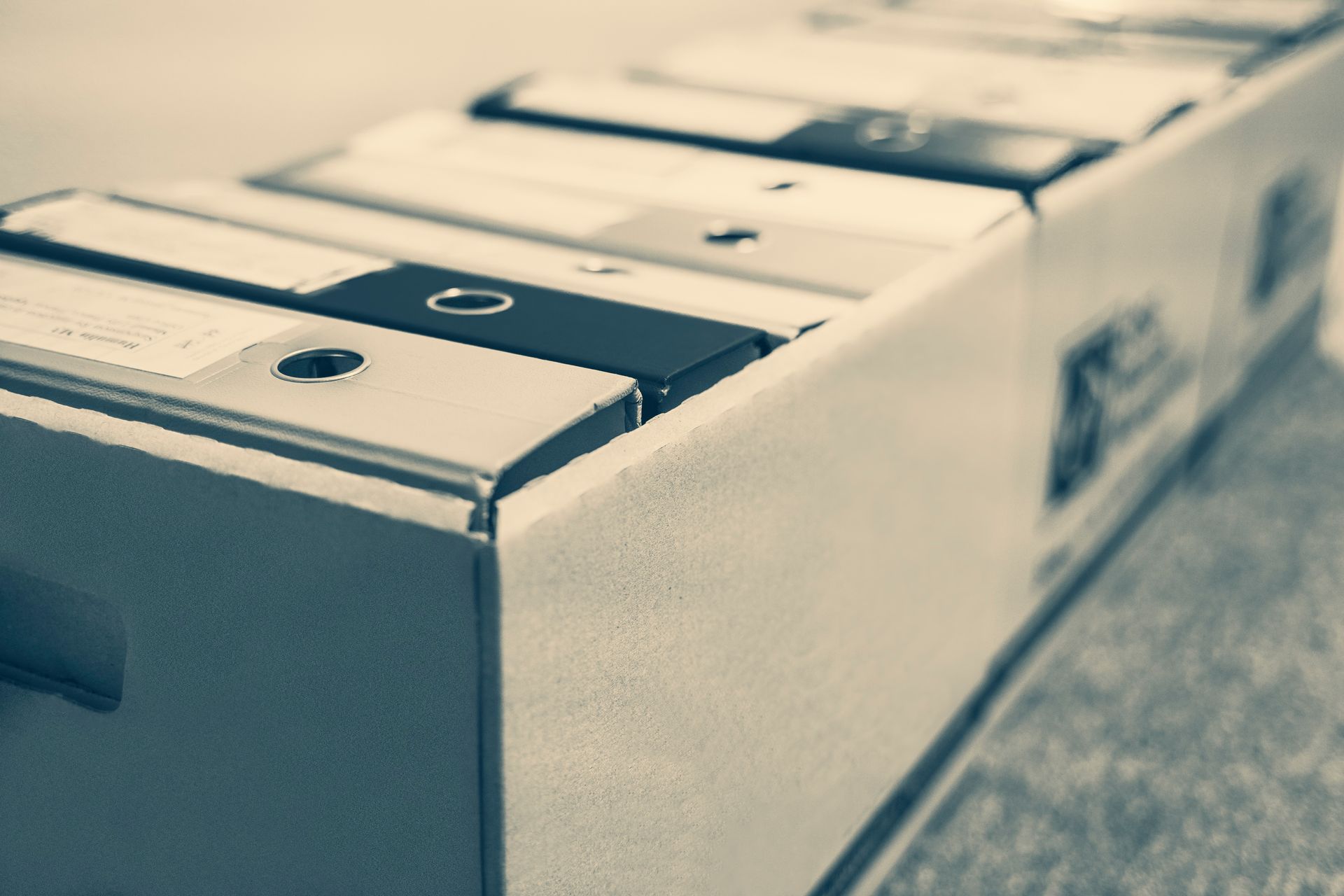 Des dossiers gris et noirs alignés dans des cartons.