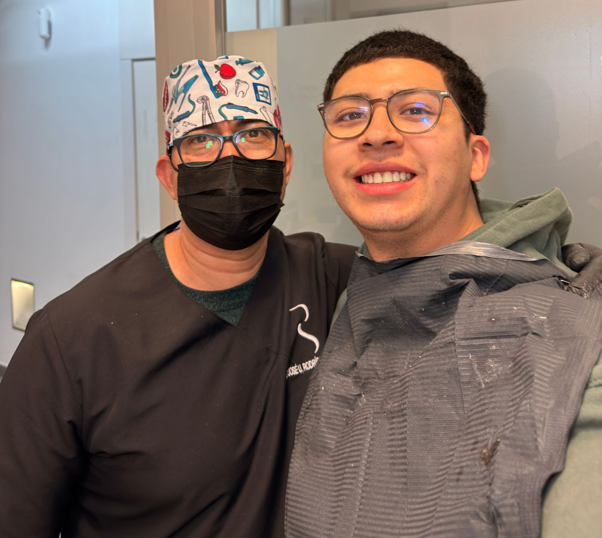 Dentista y paciente sonriendo juntos después de un procedimiento dental en una clínica.