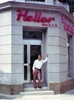 Mann steht vor dem Laden „Heller“ mit roter Beschilderung. Der Laden befindet sich in einem Eckgebäude.