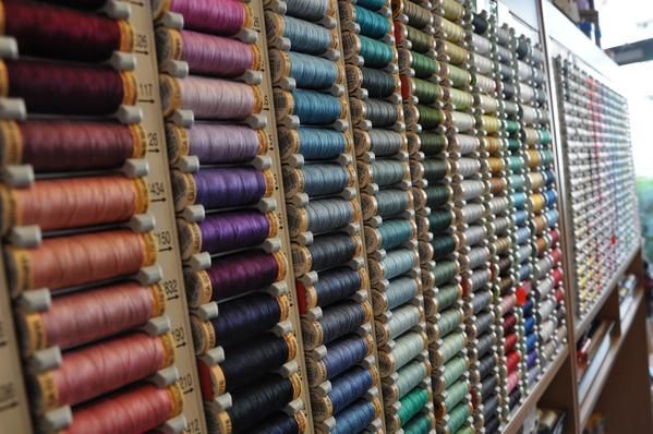 In einem Geschäft sind Reihen bunter Garnrollen in verschiedenen Schattierungen und Farbtönen ausgestellt.