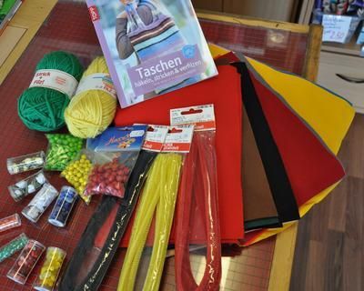 Bastelbedarf: Garn, Perlen, Stoff, Bastelbuch auf dem Tisch.