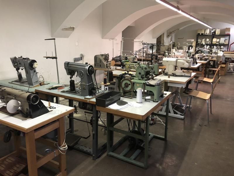 Nähmaschinen an Arbeitsplätzen in einer hell erleuchteten Werkstatt mit gewölbten Decken.