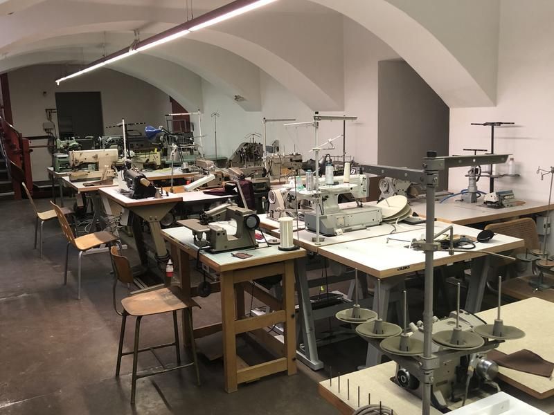 Nähwerkstatt: Mehrere Nähmaschinen auf Arbeitstischen in einem hellen, im Industriestil gestalteten Raum.