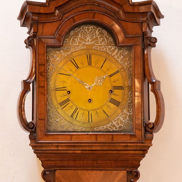 eine hölzerne Uhr mit einem gelben Zifferblatt und römischen Ziffern