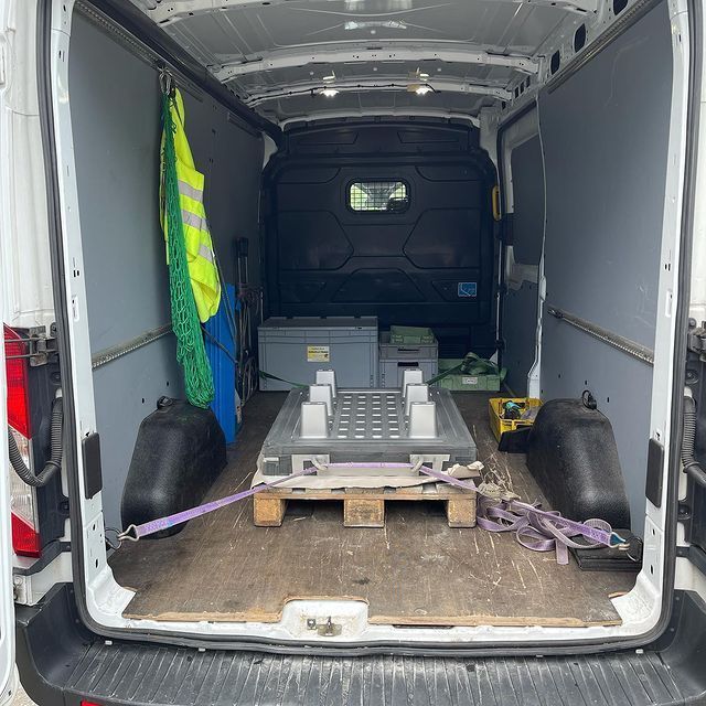 Das Innere eines Lieferwagens mit Kisten und einer Palette auf dem Boden.