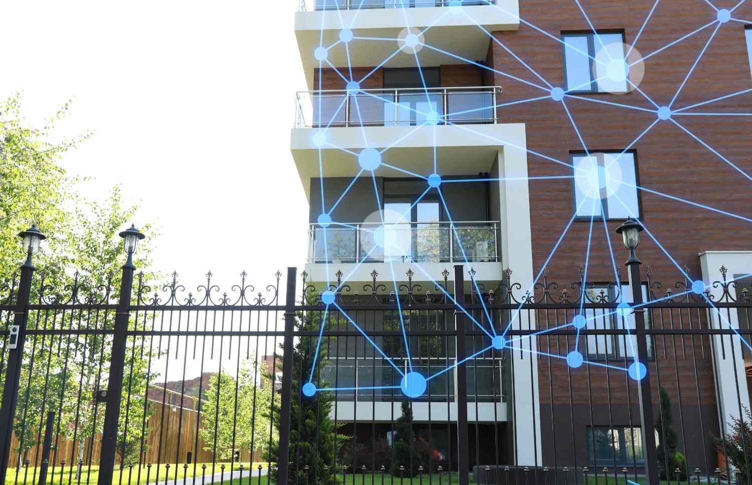Edificio de apartamentos detrás de una valla de metal negro con una superposición gráfica azul estilo red.