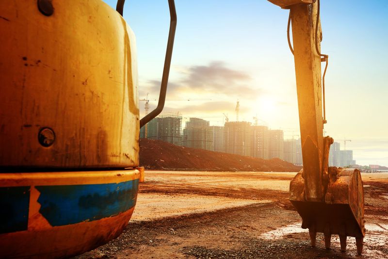 Una excavadora amarilla está trabajando en un sitio de construcción al atardecer.