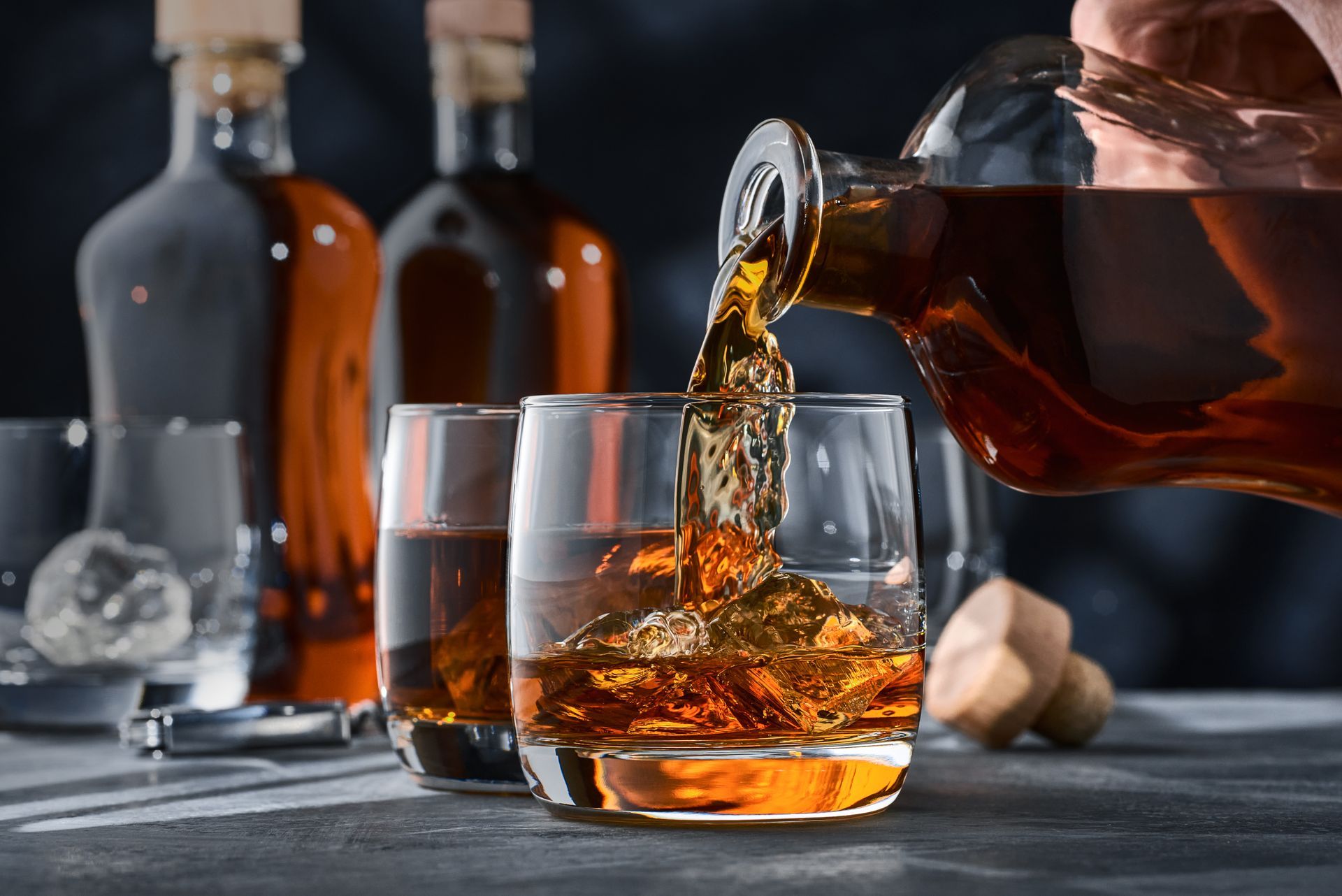 Une personne verse du whisky dans un verre avec de la glace.