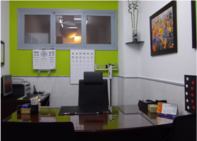 Oficina moderna con escritorio, silla negra, pared decorativa verde lima, ventana y cuadro enmarcado.