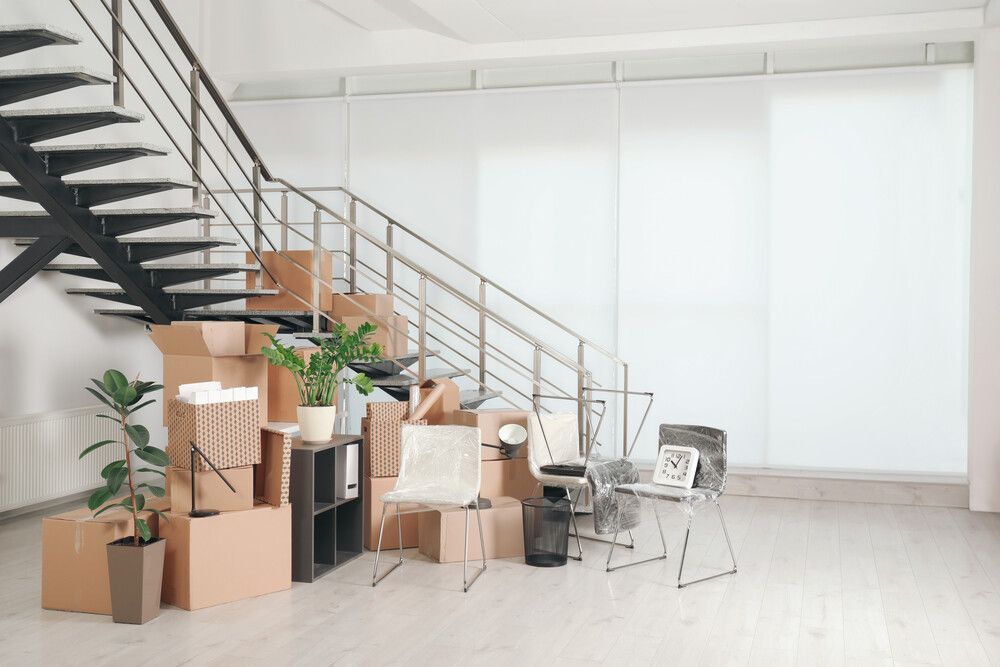 Una habitación llena de cajas y sillas debajo de una escalera.