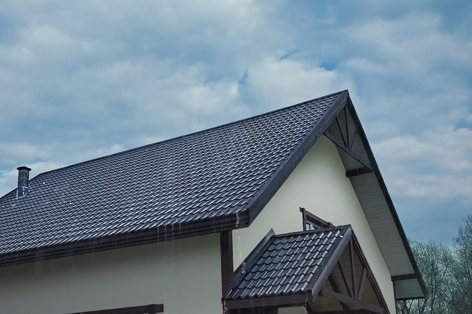 House roof with dark gray shingles under a cloudy sky