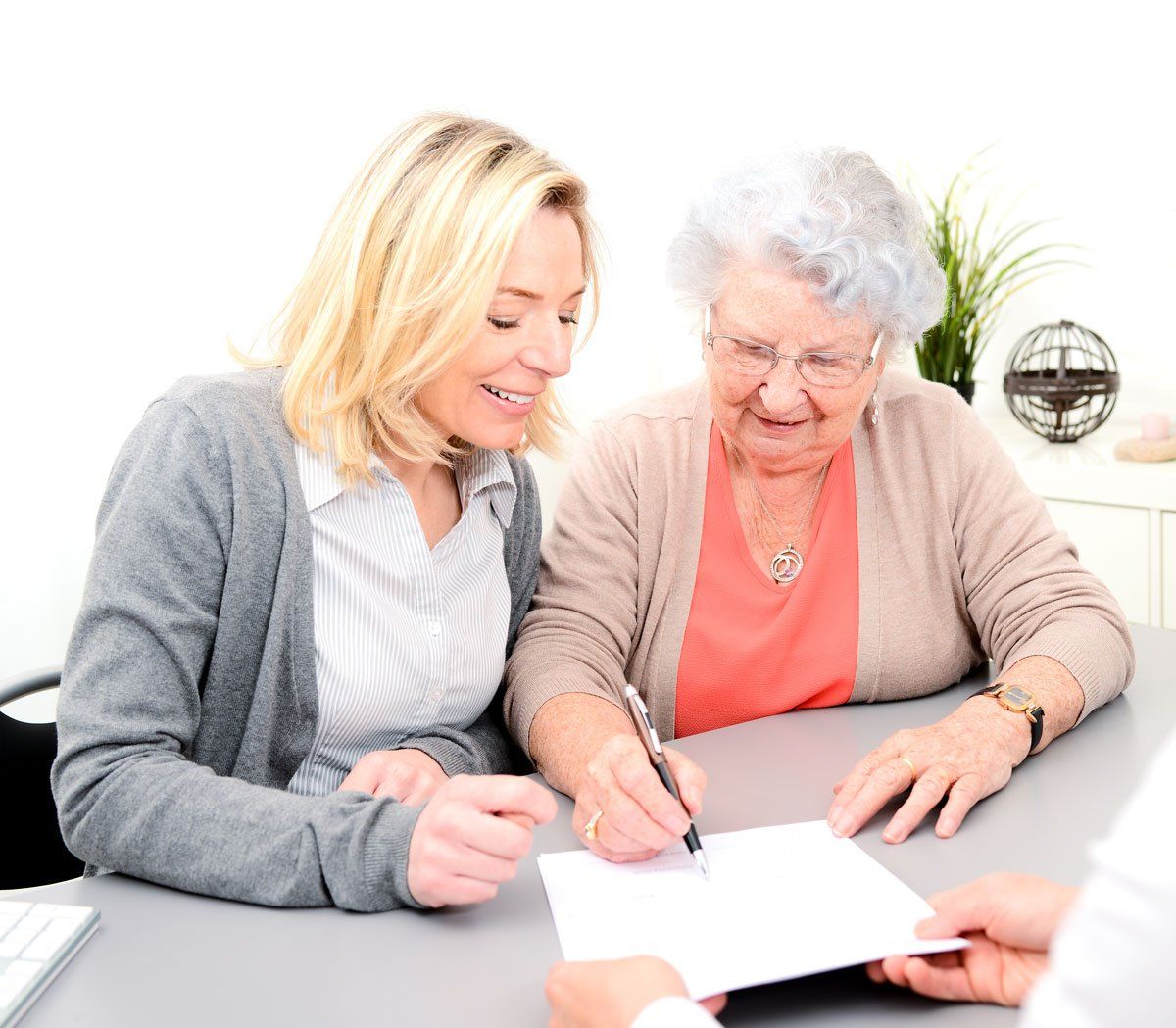 Femme âgée qui signe un contrat d'héritage en compagnie de sa fille