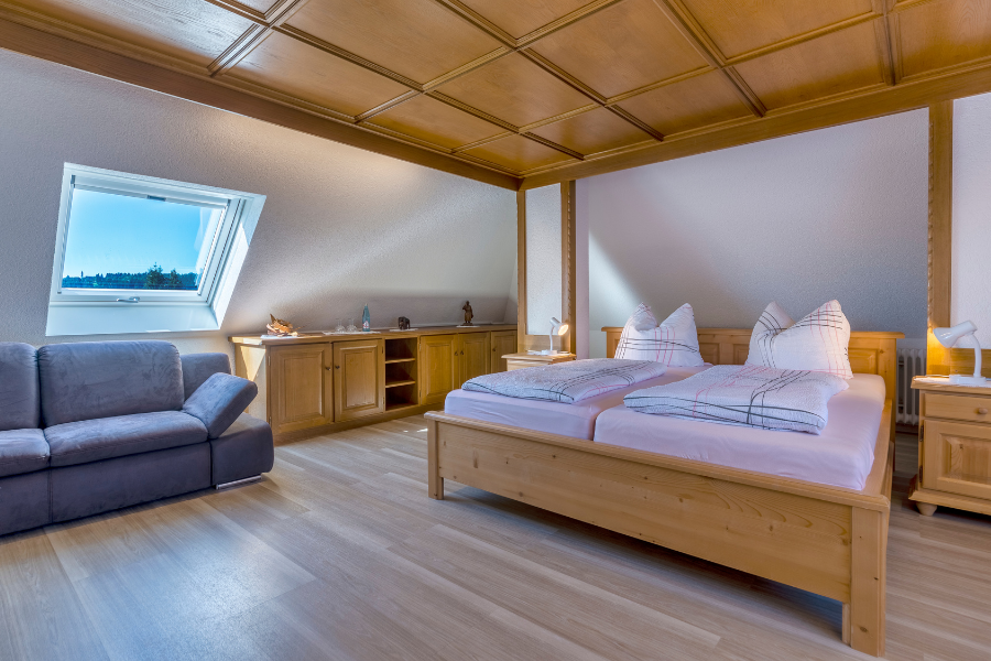 Ein Schlafzimmer mit einem Bett, einer Couch und einem Fenster | Hotel-Restaurant SchöpPerle