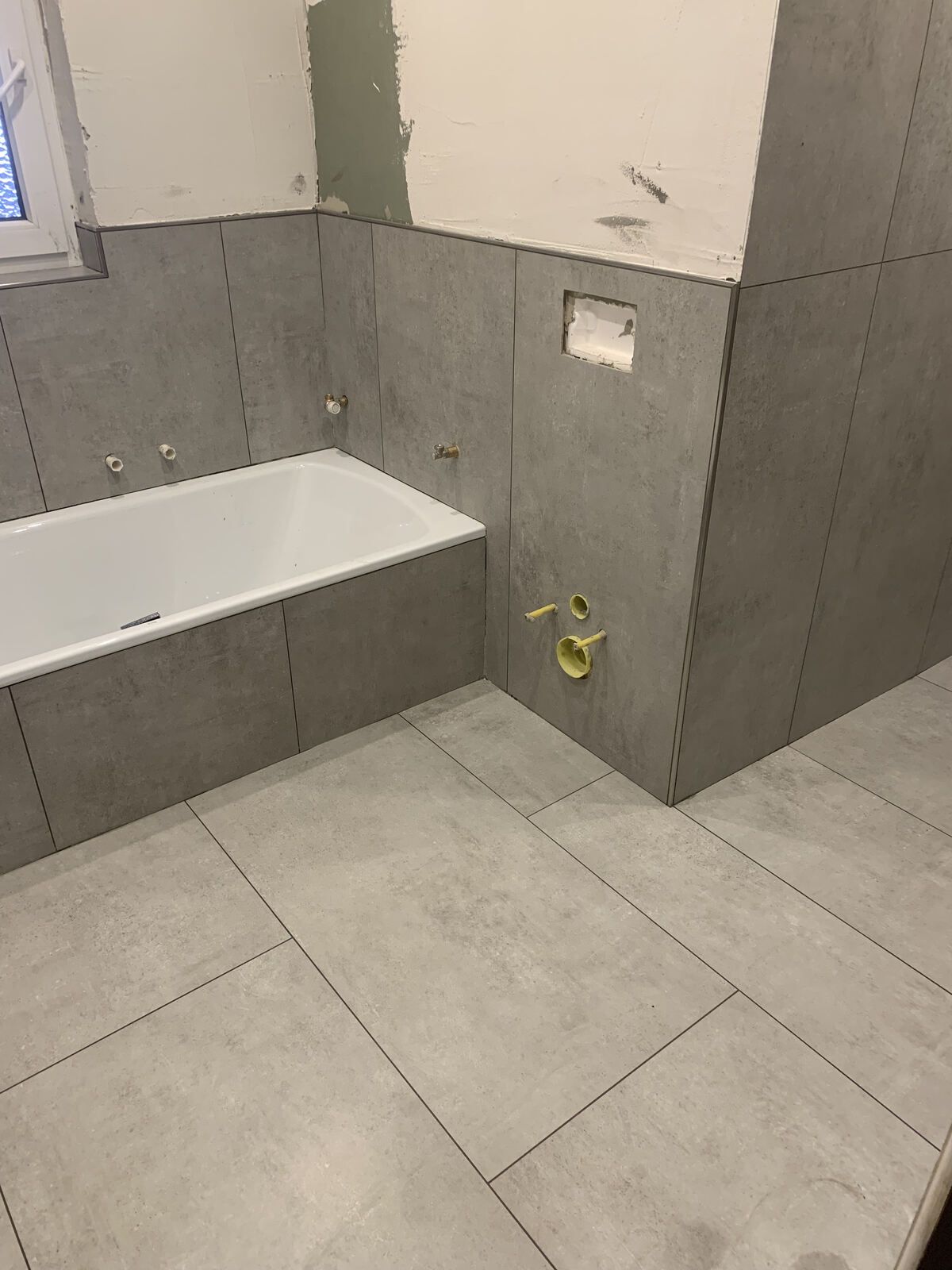 Ein Badezimmer mit Badewanne und gefliestem Boden.