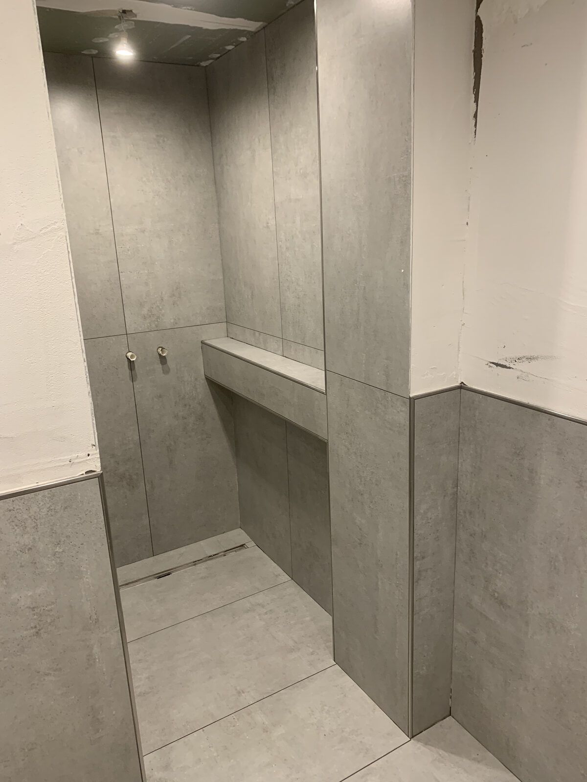 Ein Badezimmer mit ebenerdiger Dusche und Waschbecken.