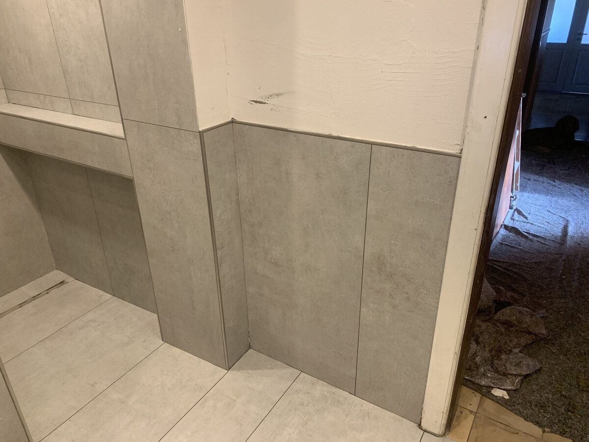 Ein im Bau befindliches Badezimmer mit Fliesen an Wand und Boden.